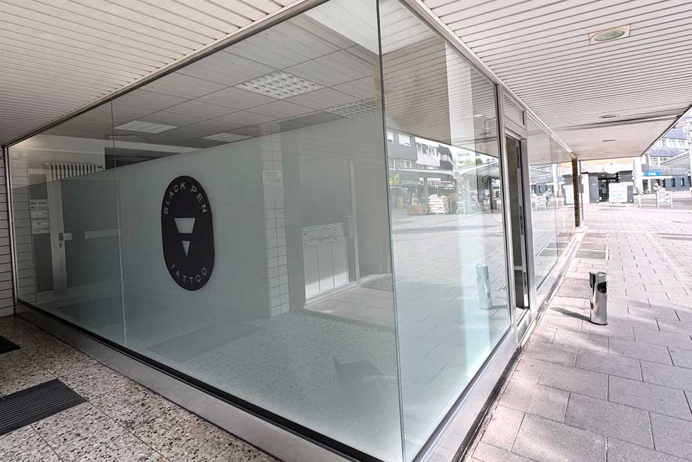 Glasfassade eines modernen Geschäftsgebäudes mit einem minimalistischen Logo im Eingangsbereich.